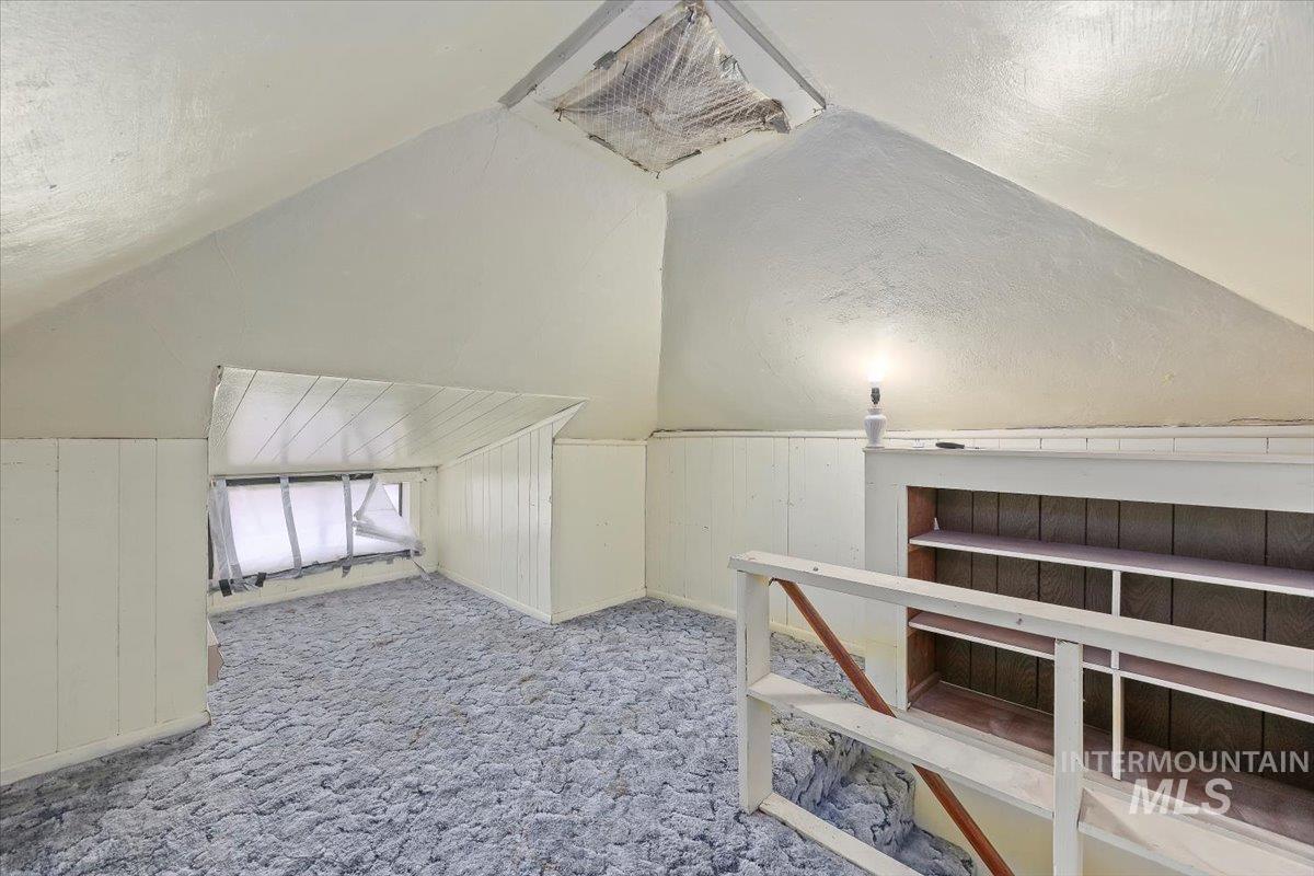 Additional living space featuring wooden walls, a textured ceiling, carpet, and vaulted ceiling