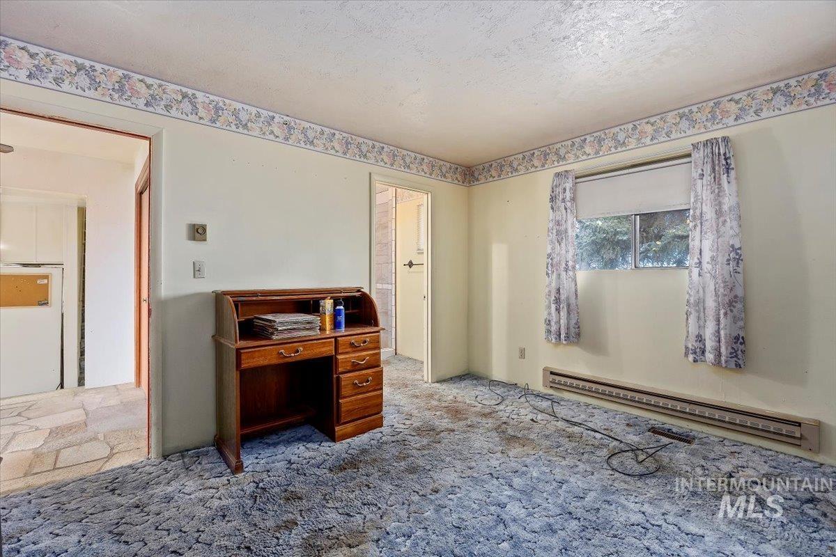 Carpeted bedroom with baseboard heating and a textured ceiling