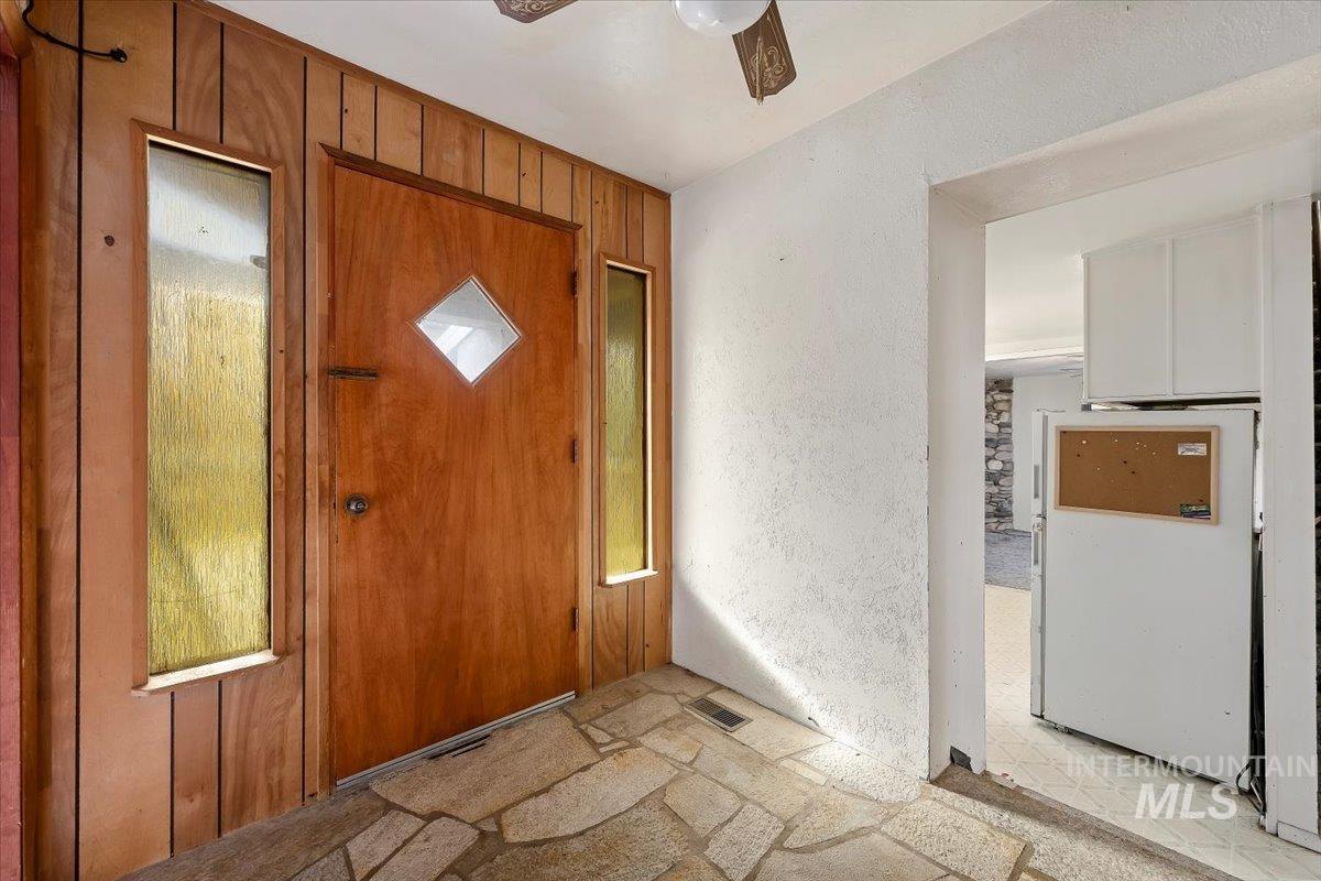 Foyer with ceiling fan and a textured wall