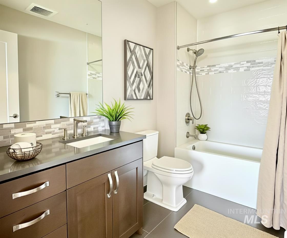 Full bath featuring shower / bath combo with shower curtain, vanity, decorative backsplash, and dark tile patterned floors