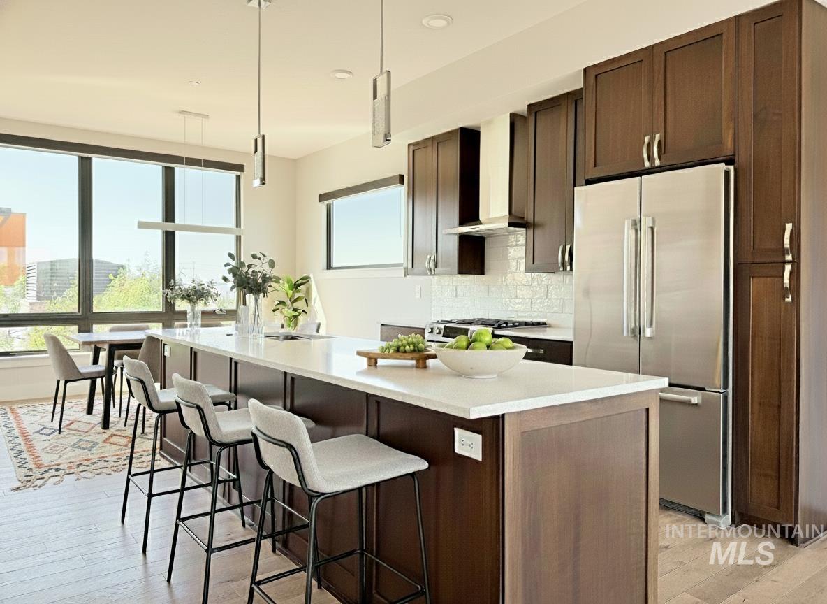 Kitchen featuring high quality fridge, dark brown cabinets, and light wood-type flooring