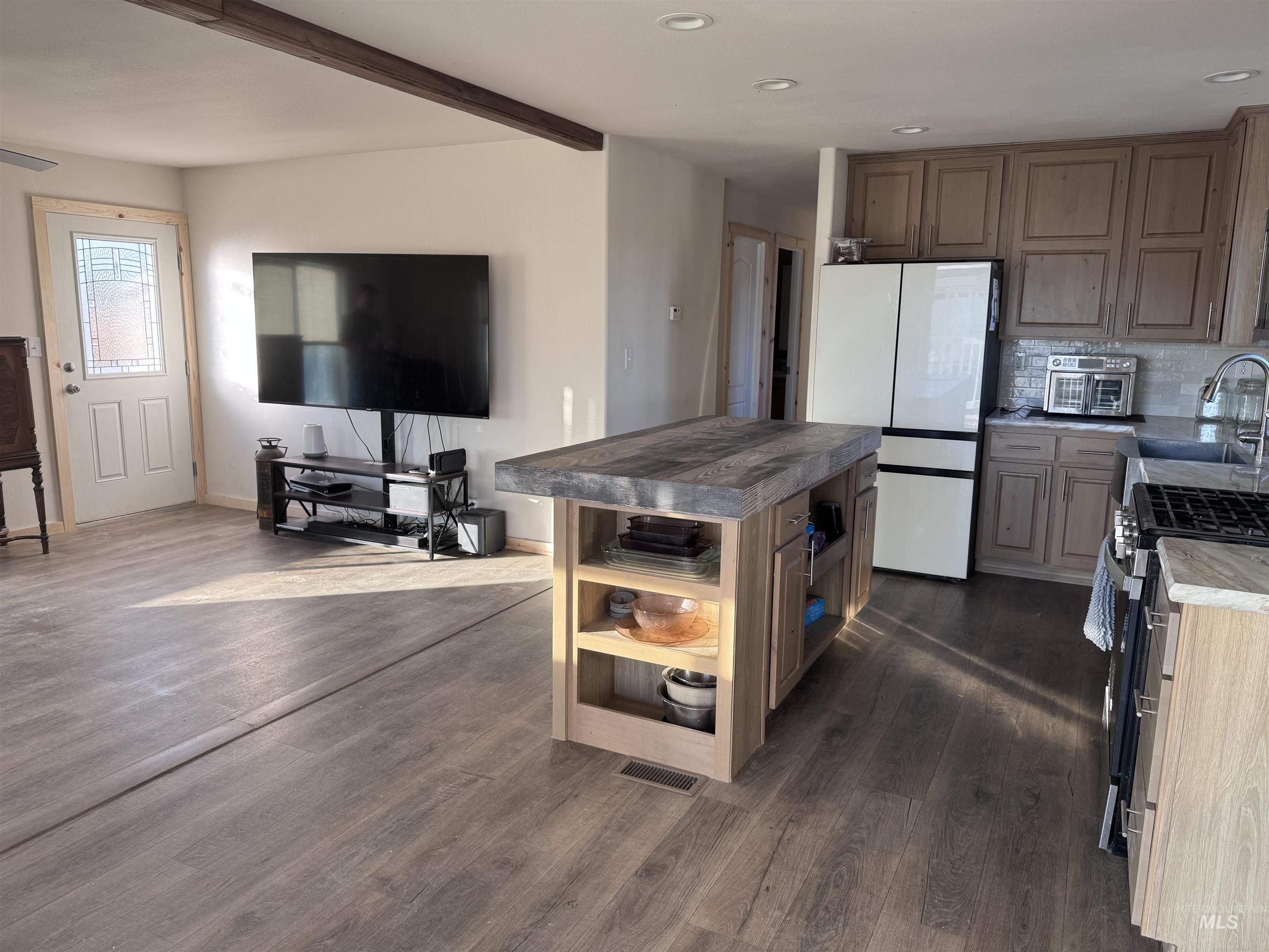 Kitchen with open shelves, backsplash, freestanding refrigerator, a center island, and dark wood-style flooring