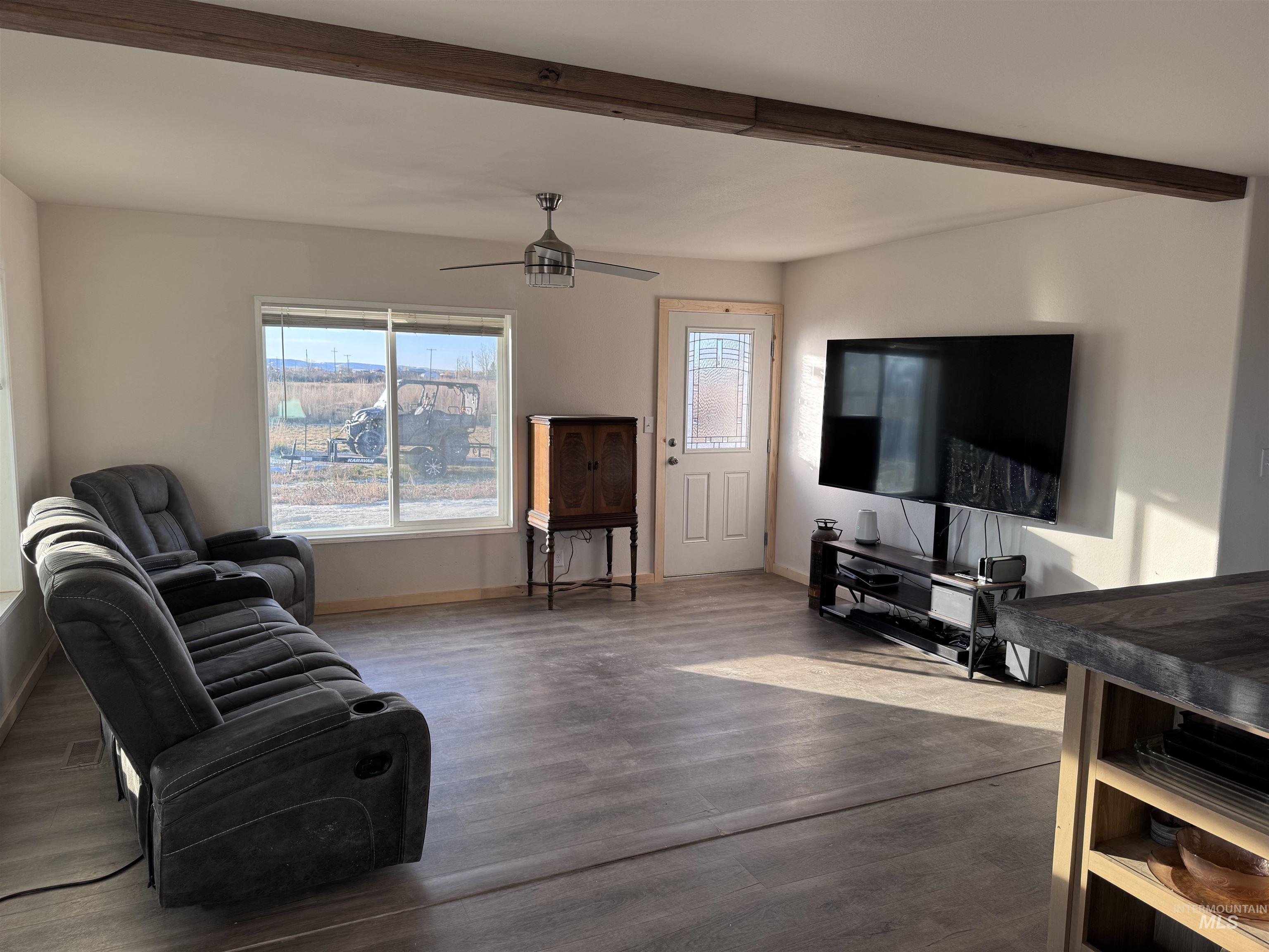 Living room with wood finished floors, beam ceiling, and ceiling fan