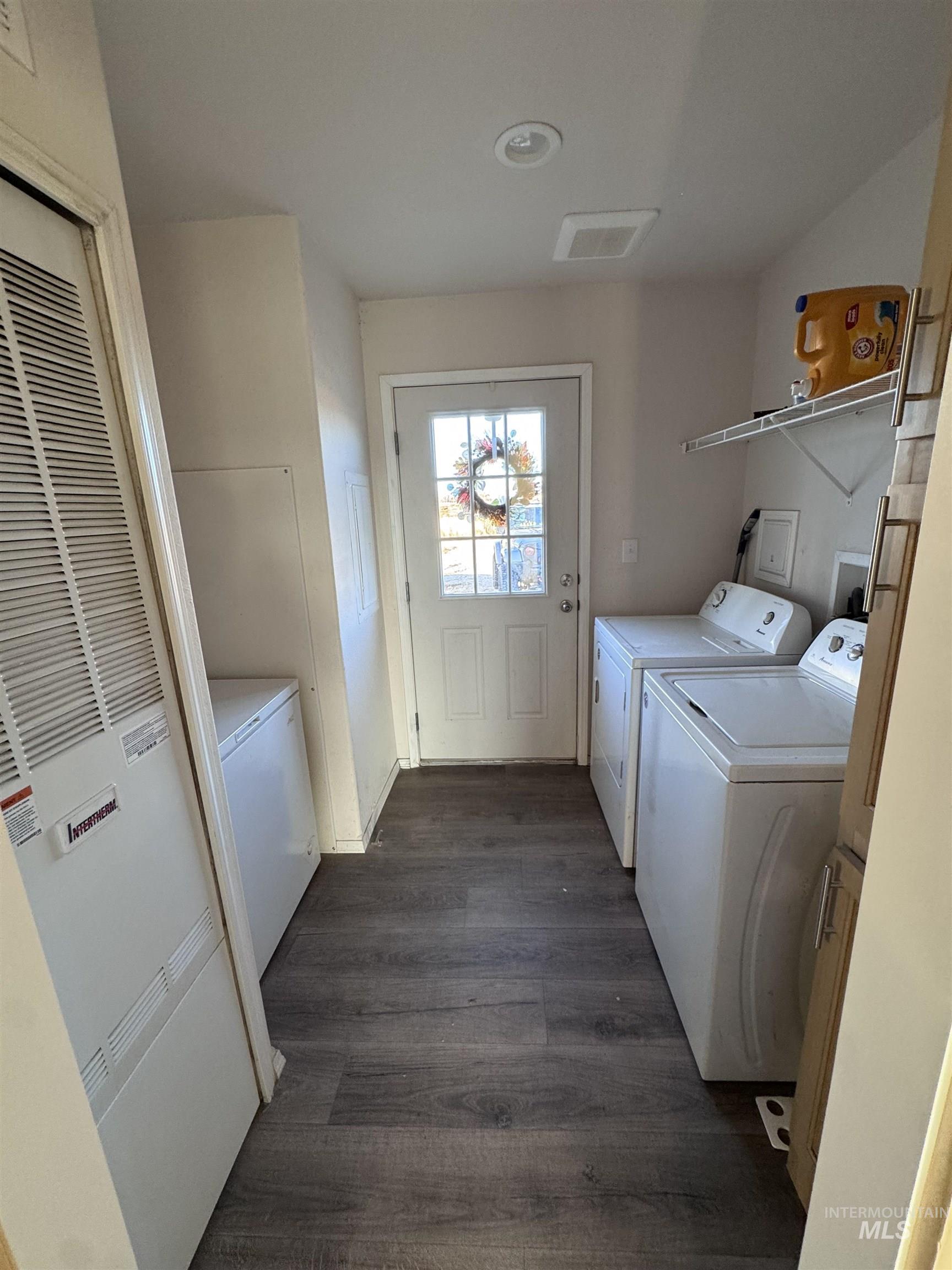 Laundry area featuring a heating unit, dark wood-style flooring, and washing machine and clothes dryer