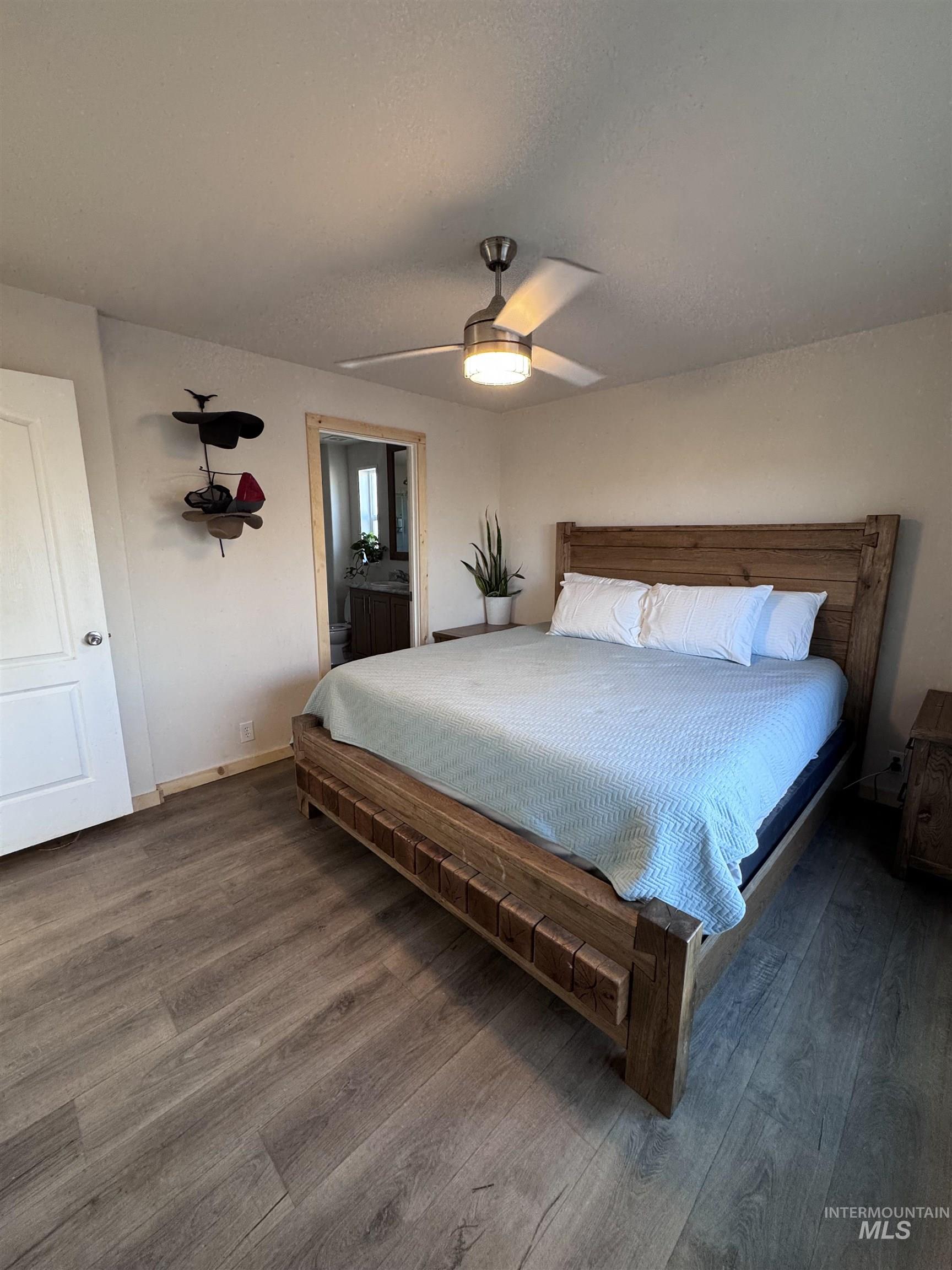 Bedroom with wood finished floors, a ceiling fan, and connected bathroom