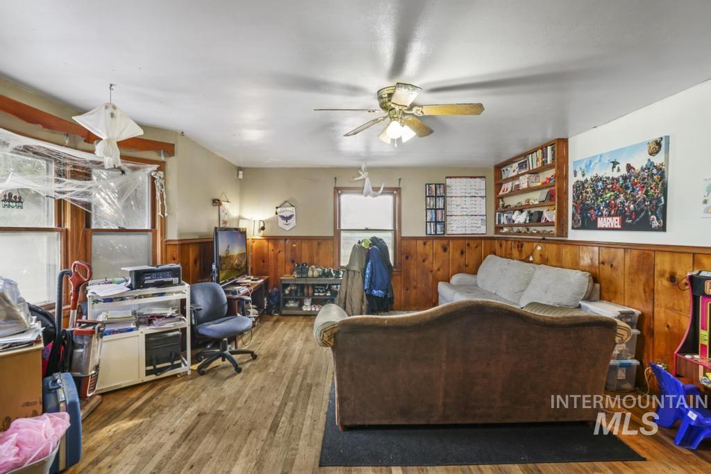 Office featuring wood finished floors, ceiling fan, wainscoting, and wood walls