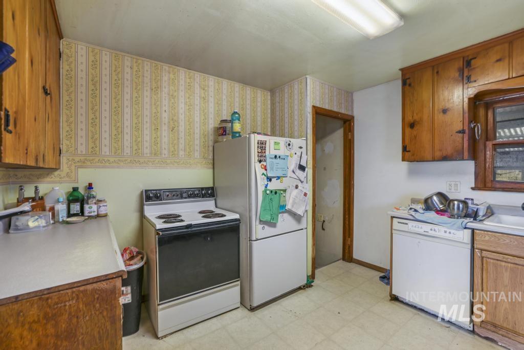 Kitchen with light flooring, white appliances, light countertops, and brown cabinets