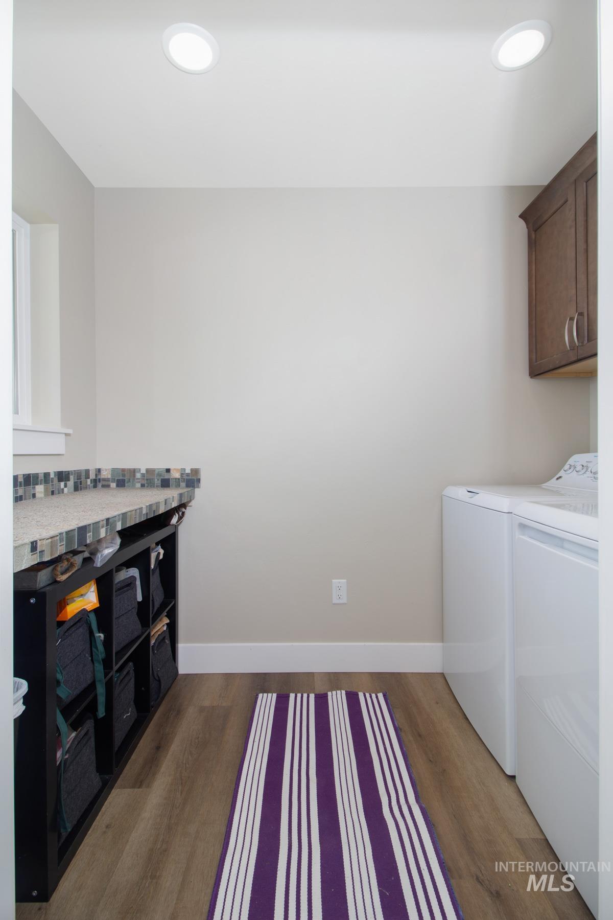 Laundry room with cabinet space, dark wood-type flooring, separate washer and dryer, and recessed lighting
