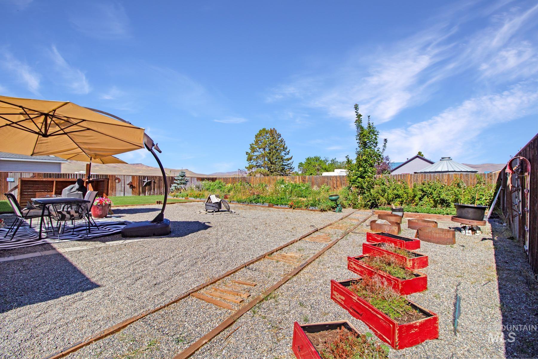 Fenced backyard featuring a patio and a vegetable garden