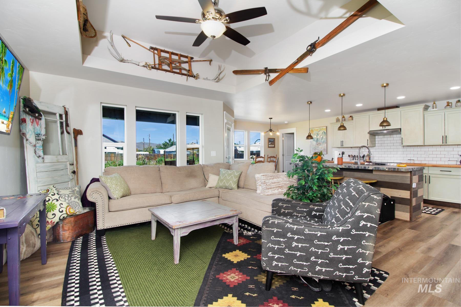 Living room with light wood-type flooring, a ceiling fan, and a tray ceiling
