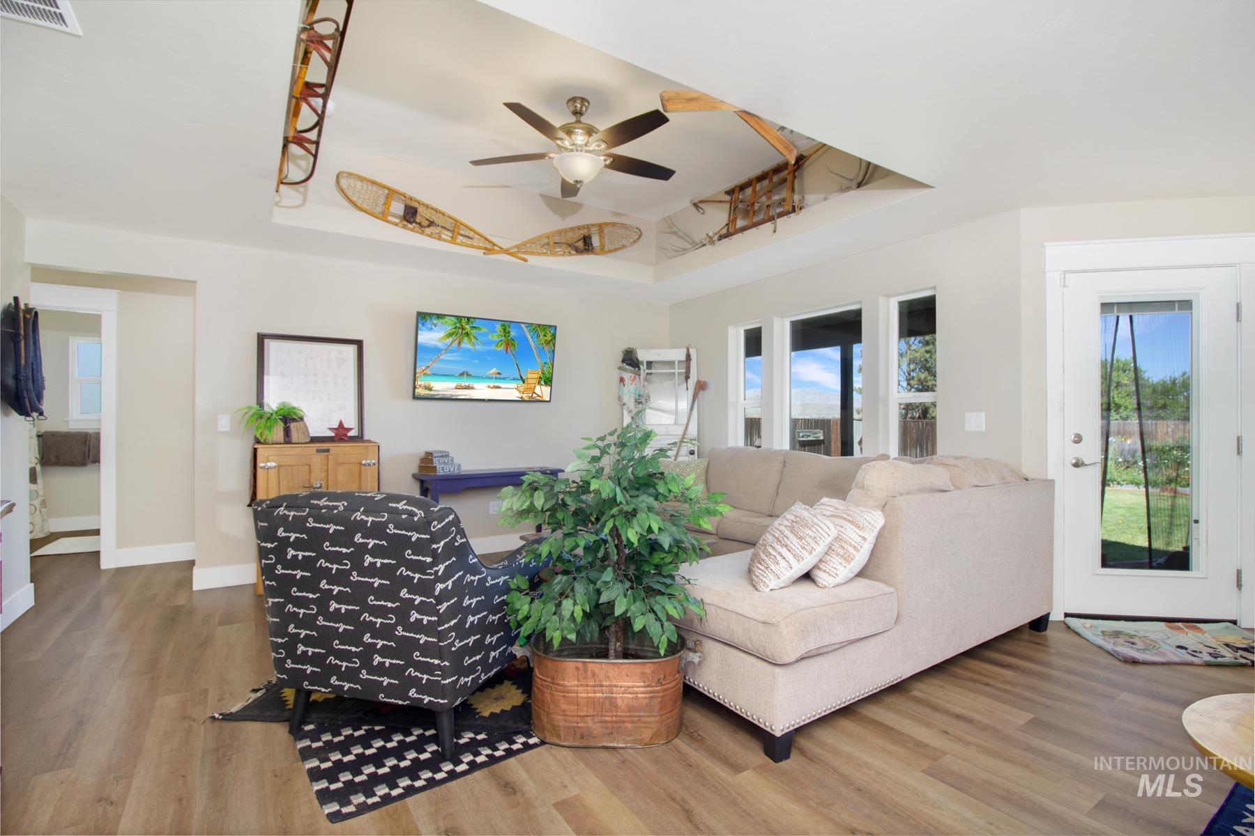 Living area featuring a tray ceiling, wood finished floors, and a ceiling fan