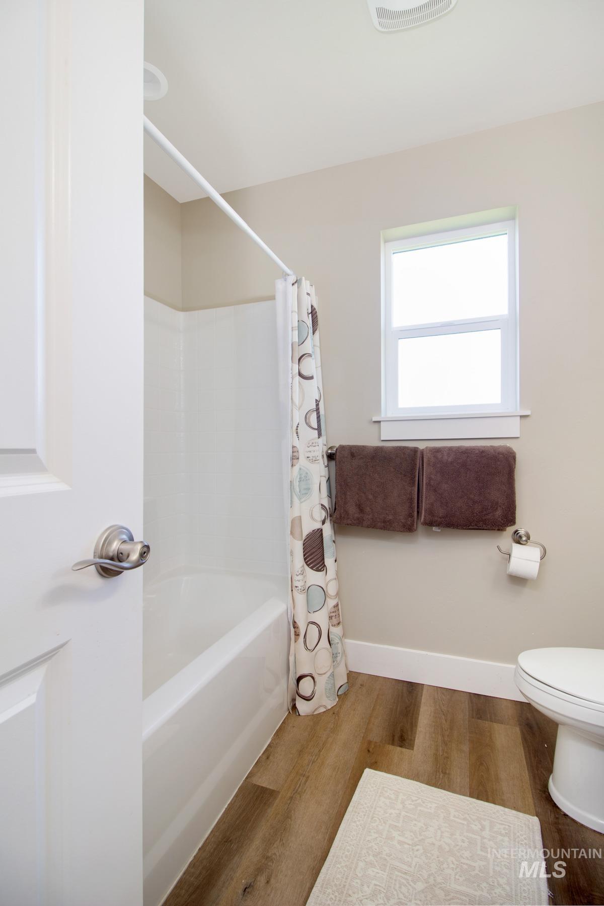 Bathroom with wood finished floors and shower / bath combination with curtain