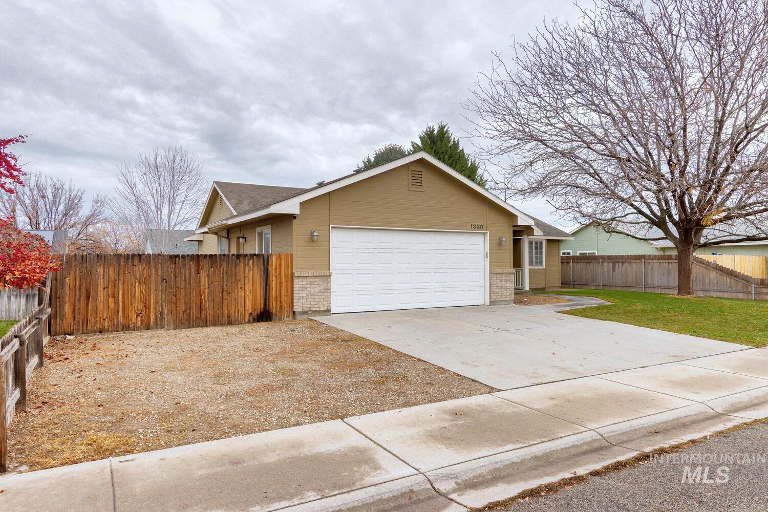 Single story home with driveway, brick siding, and an attached garage