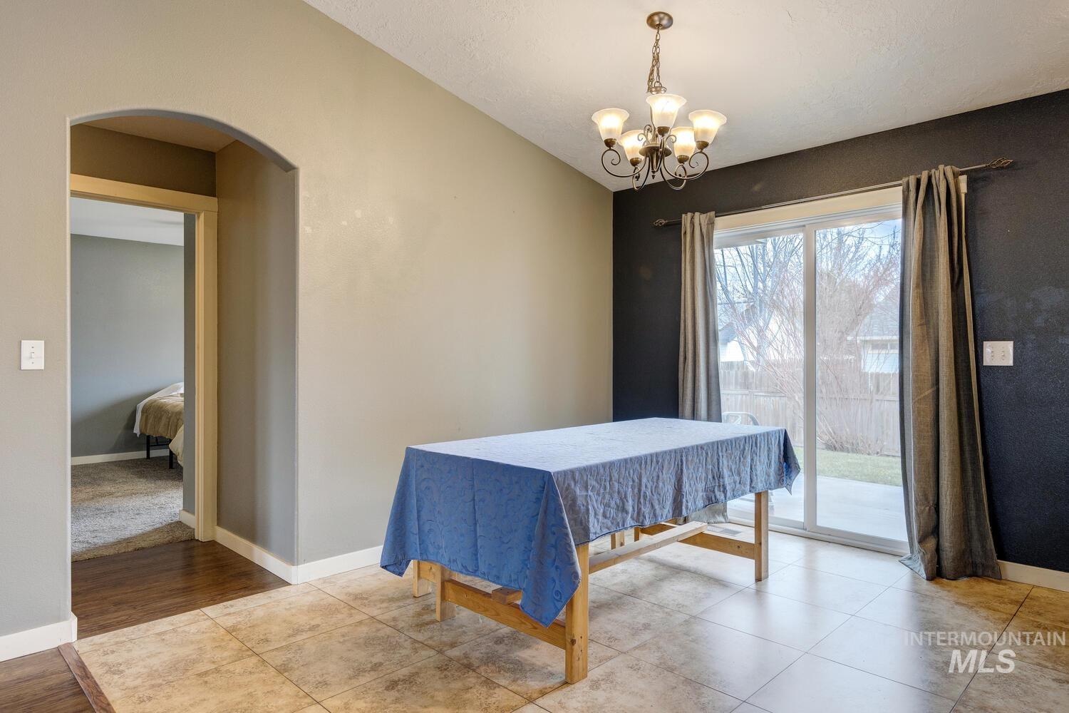 Tiled dining area featuring arched walkways and a chandelier