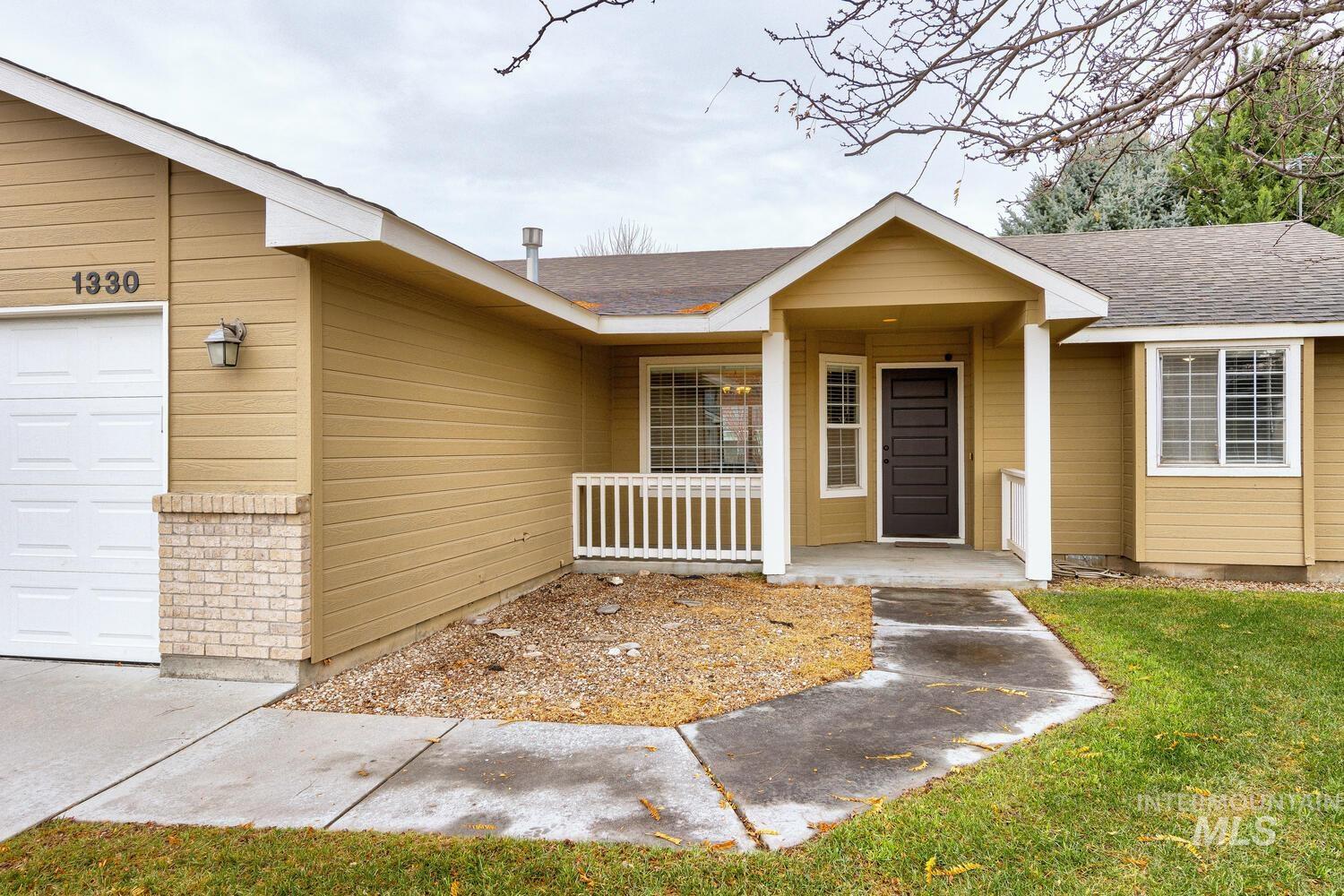 View of exterior entry with an attached garage, roof with shingles, and covered porch