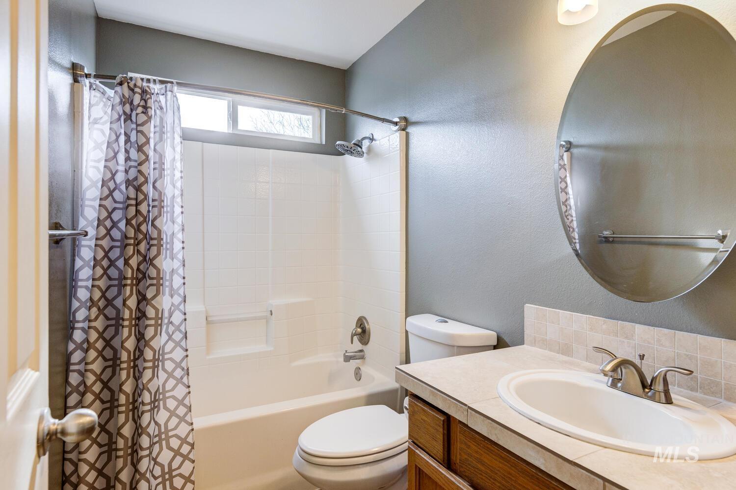 Bathroom with shower / bathtub combination with curtain, vanity, and a textured wall