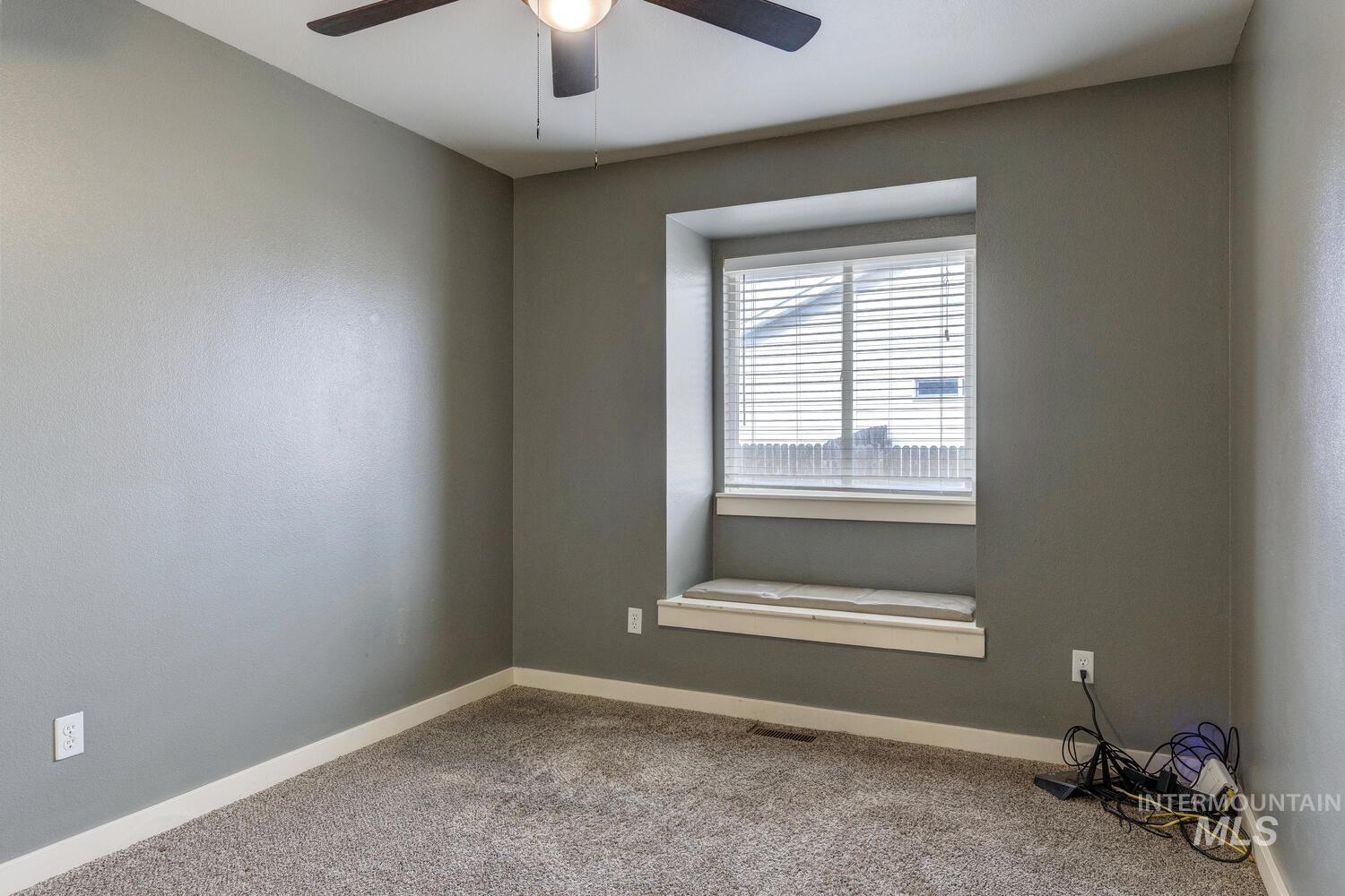 Carpeted spare room with baseboards and a ceiling fan
