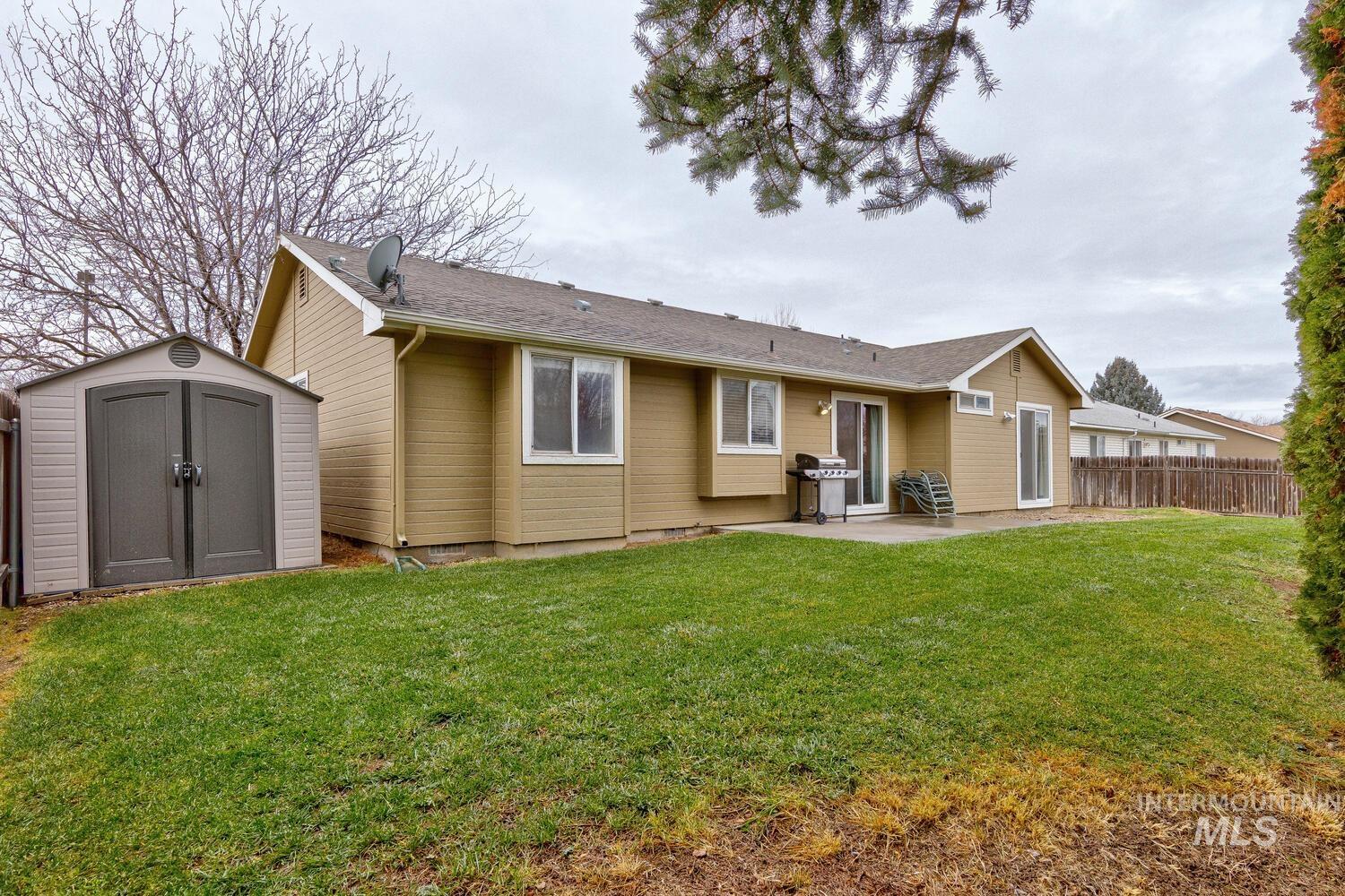 Rear view of property with a storage shed and a patio area