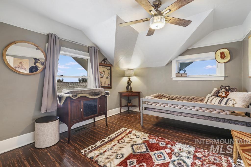 Living area with lofted ceiling, dark wood-style flooring, plenty of natural light, and a ceiling fan