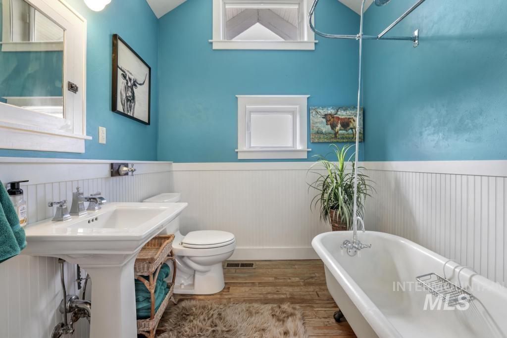 Full bathroom featuring light wood-style flooring, a freestanding bath, and wainscoting