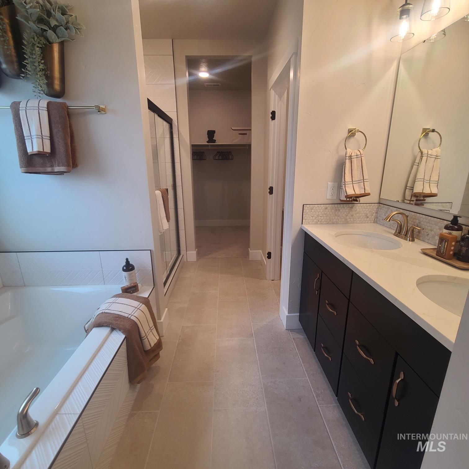 Bathroom with a bath, a stall shower, double vanity, and light tile patterned flooring
