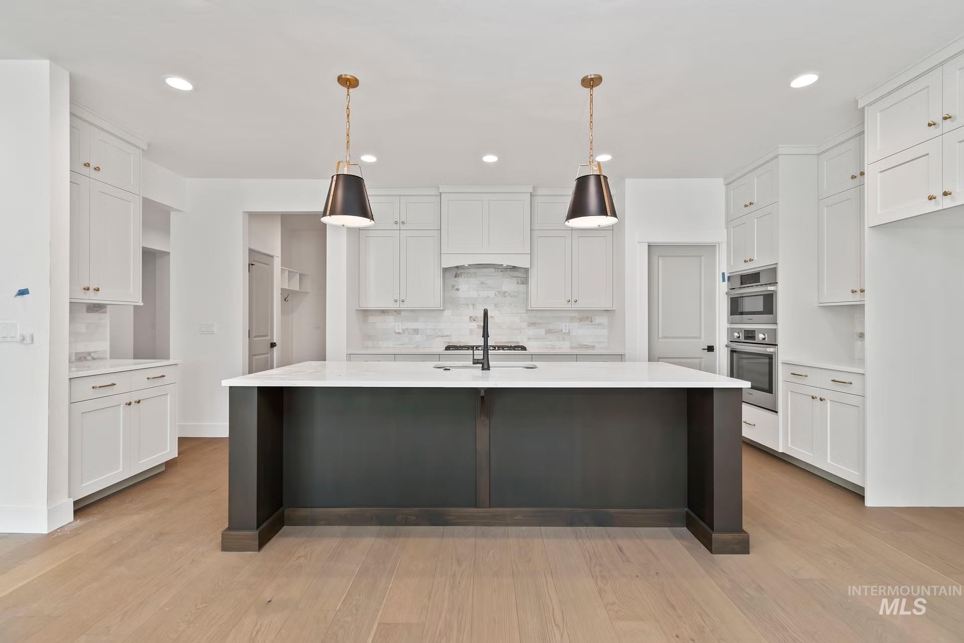 Kitchen with backsplash, white cabinetry, pendant lighting, light wood-type flooring, and recessed lighting