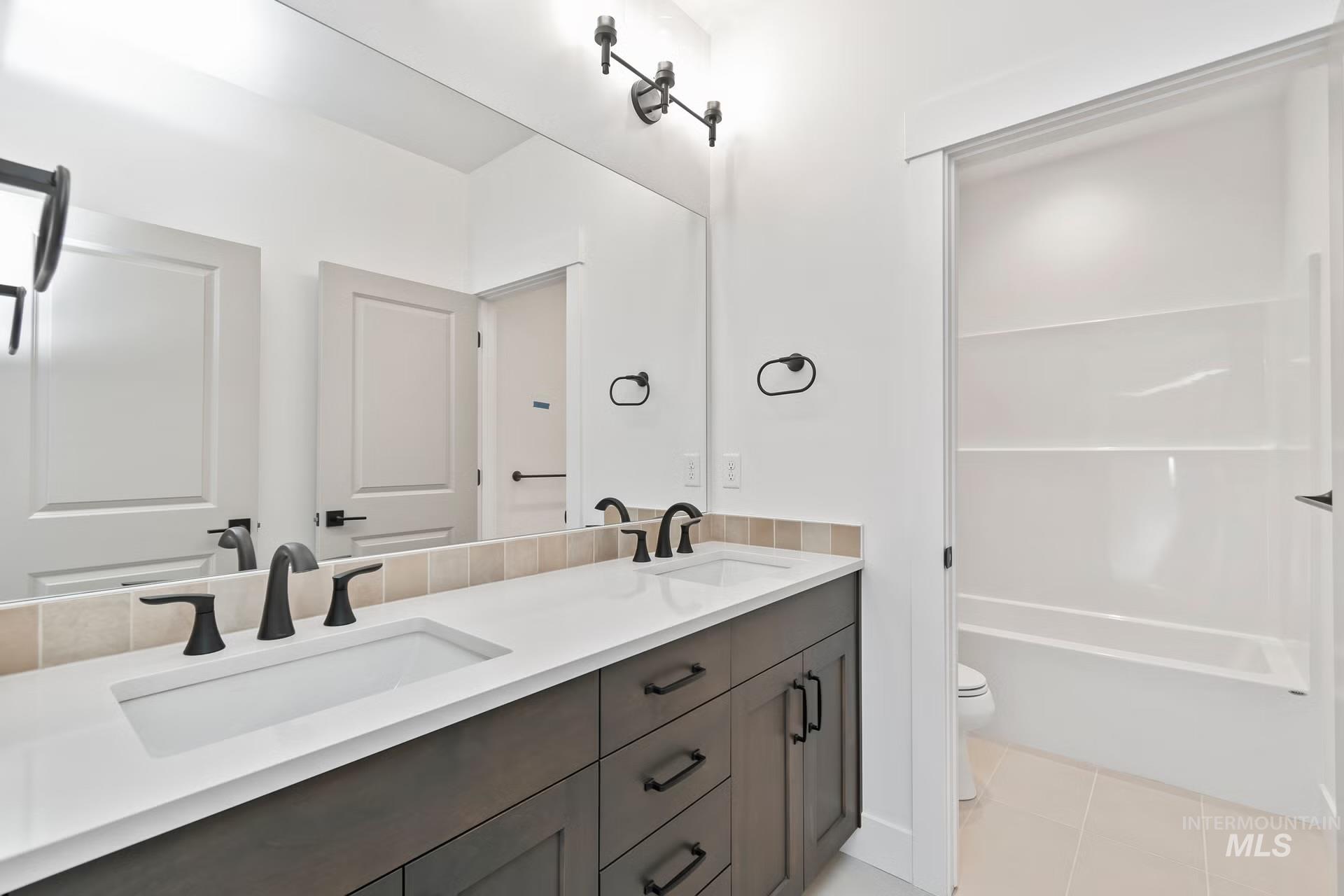 Full bathroom featuring double vanity and light tile patterned floors