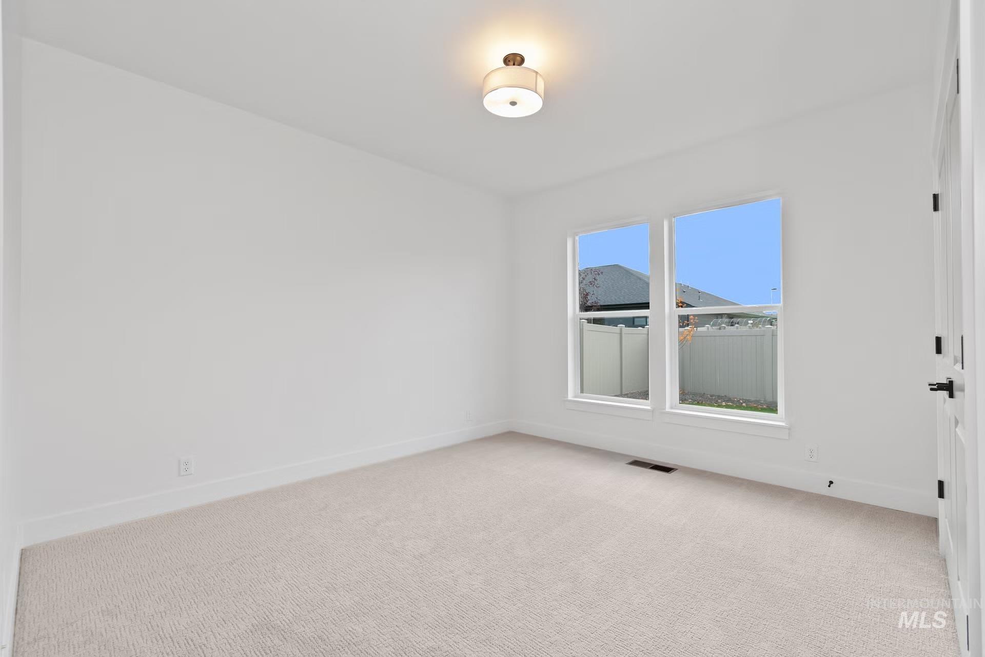 Spare room featuring light carpet and baseboards