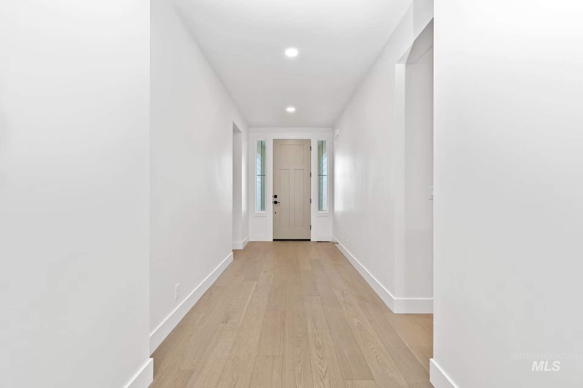 Hallway with light wood-type flooring and recessed lighting