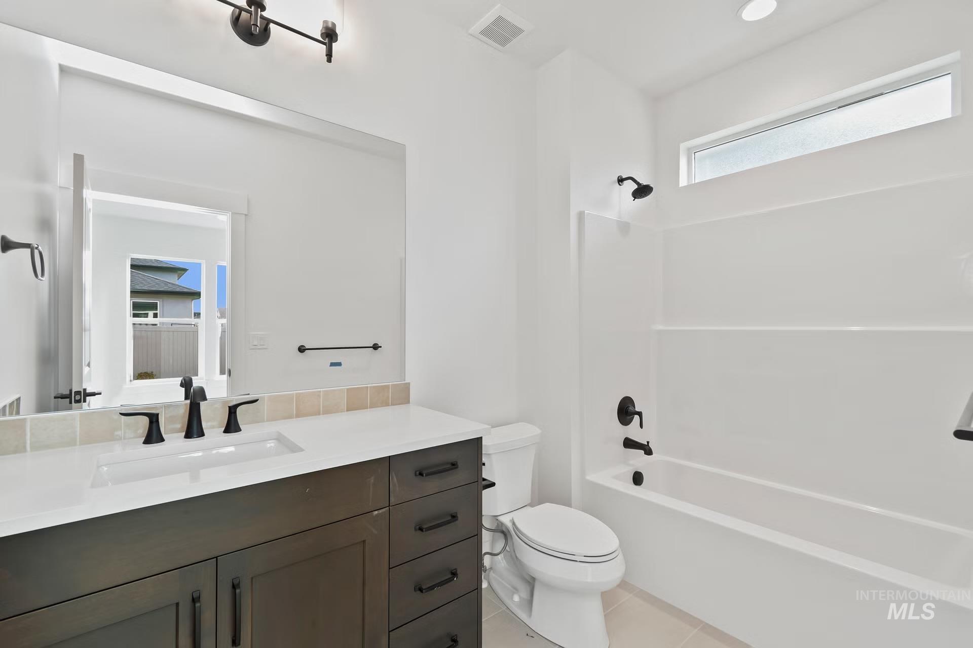 Full bath featuring tub / shower combination, vanity, and light tile patterned flooring