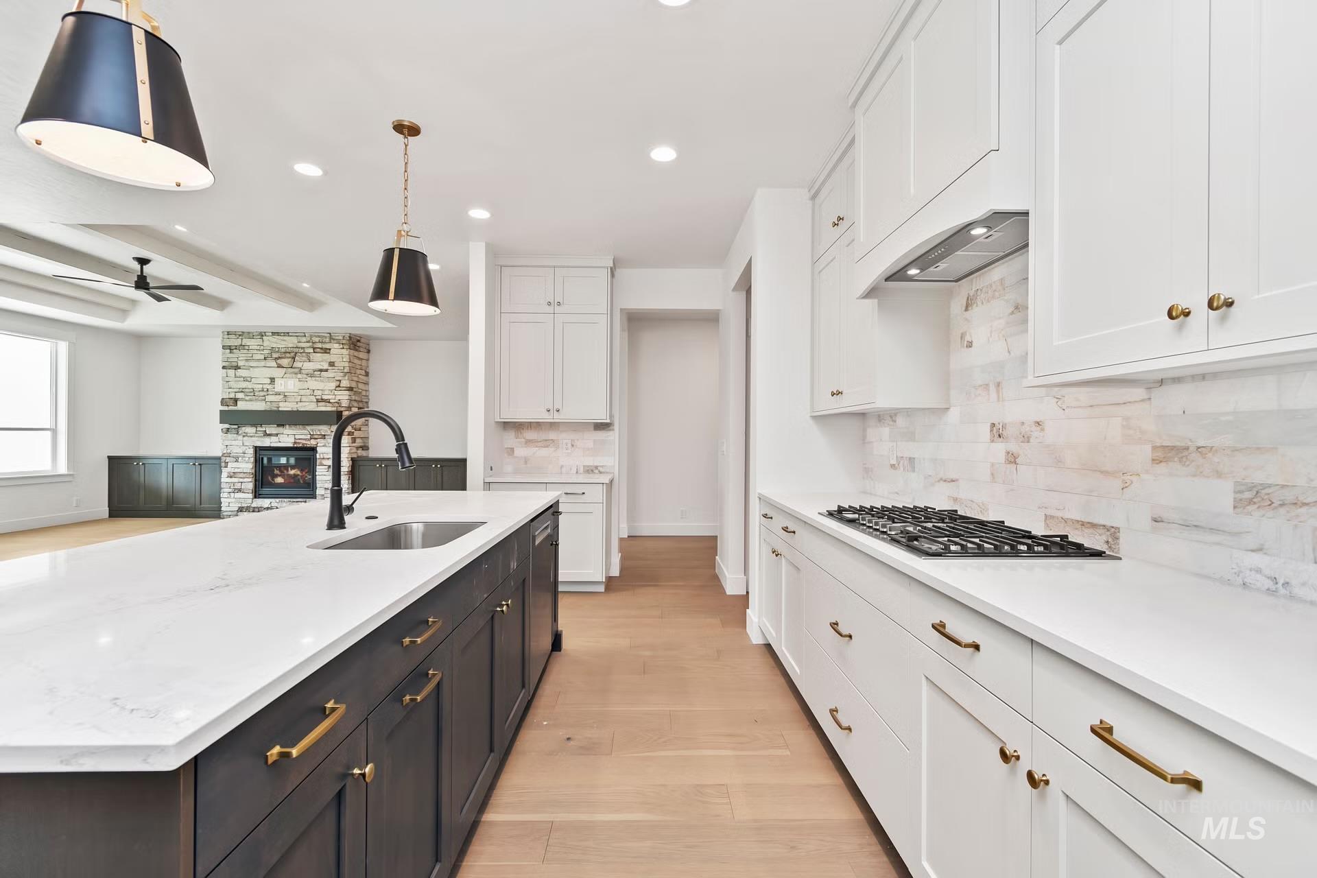 Kitchen featuring white cabinetry, a stone fireplace, light wood-type flooring, recessed lighting, and decorative light fixtures