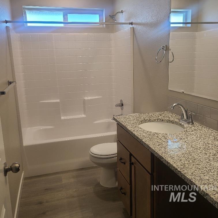 Bathroom with vanity, shower / bath combination, and dark wood-type flooring