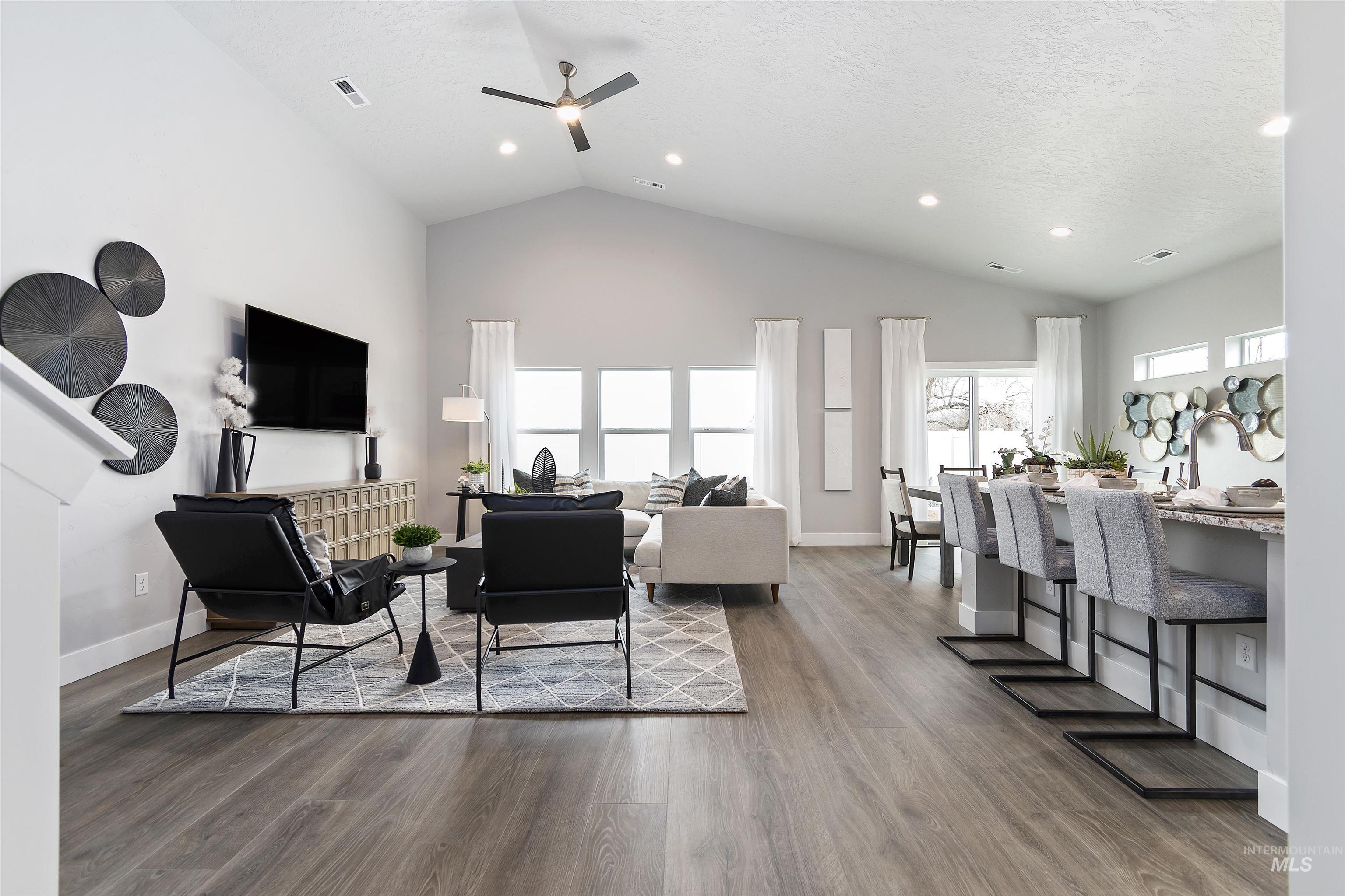 Living area with wood finished floors, high vaulted ceiling, a ceiling fan, recessed lighting, and a textured ceiling