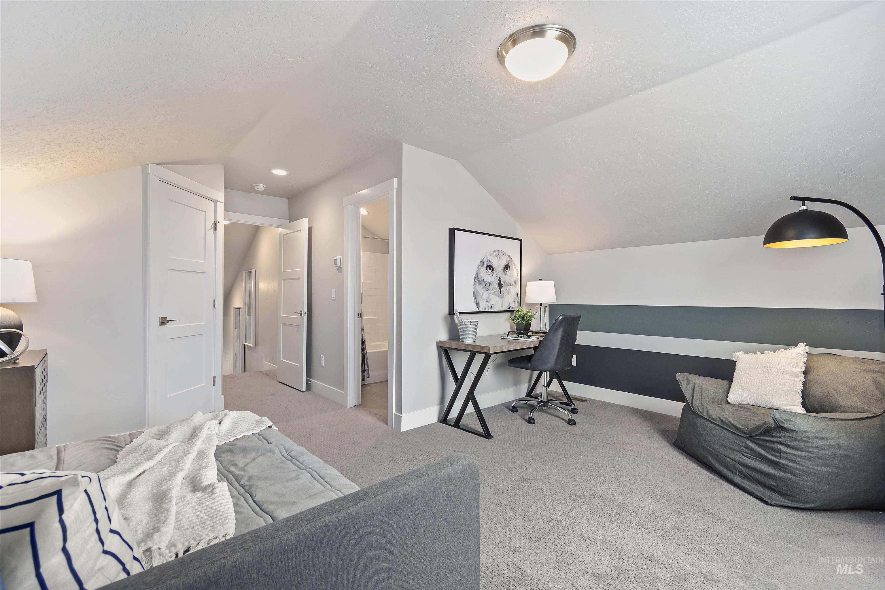 Carpeted office space featuring vaulted ceiling and a textured ceiling