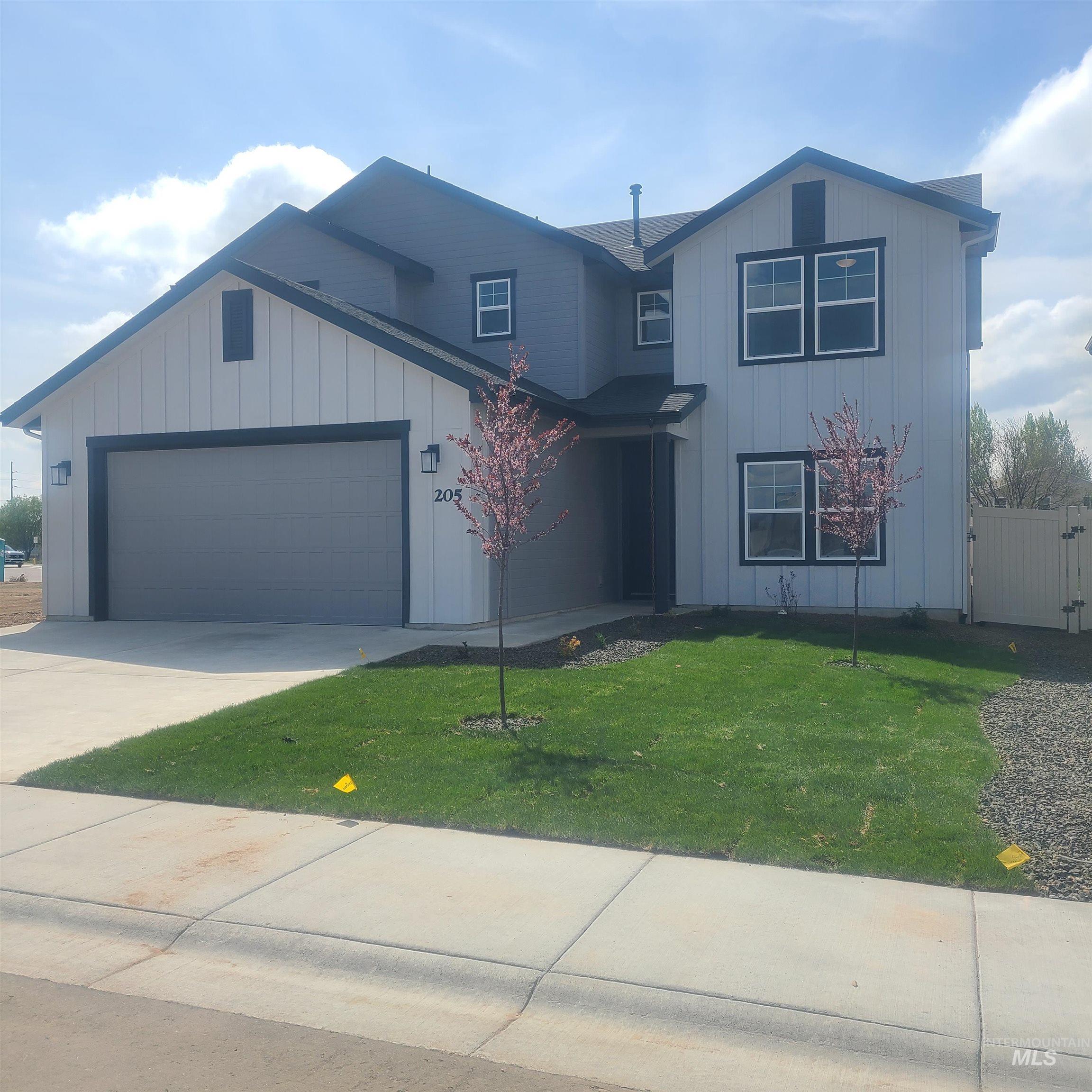 View of front of property with board and batten siding, driveway, and a garage