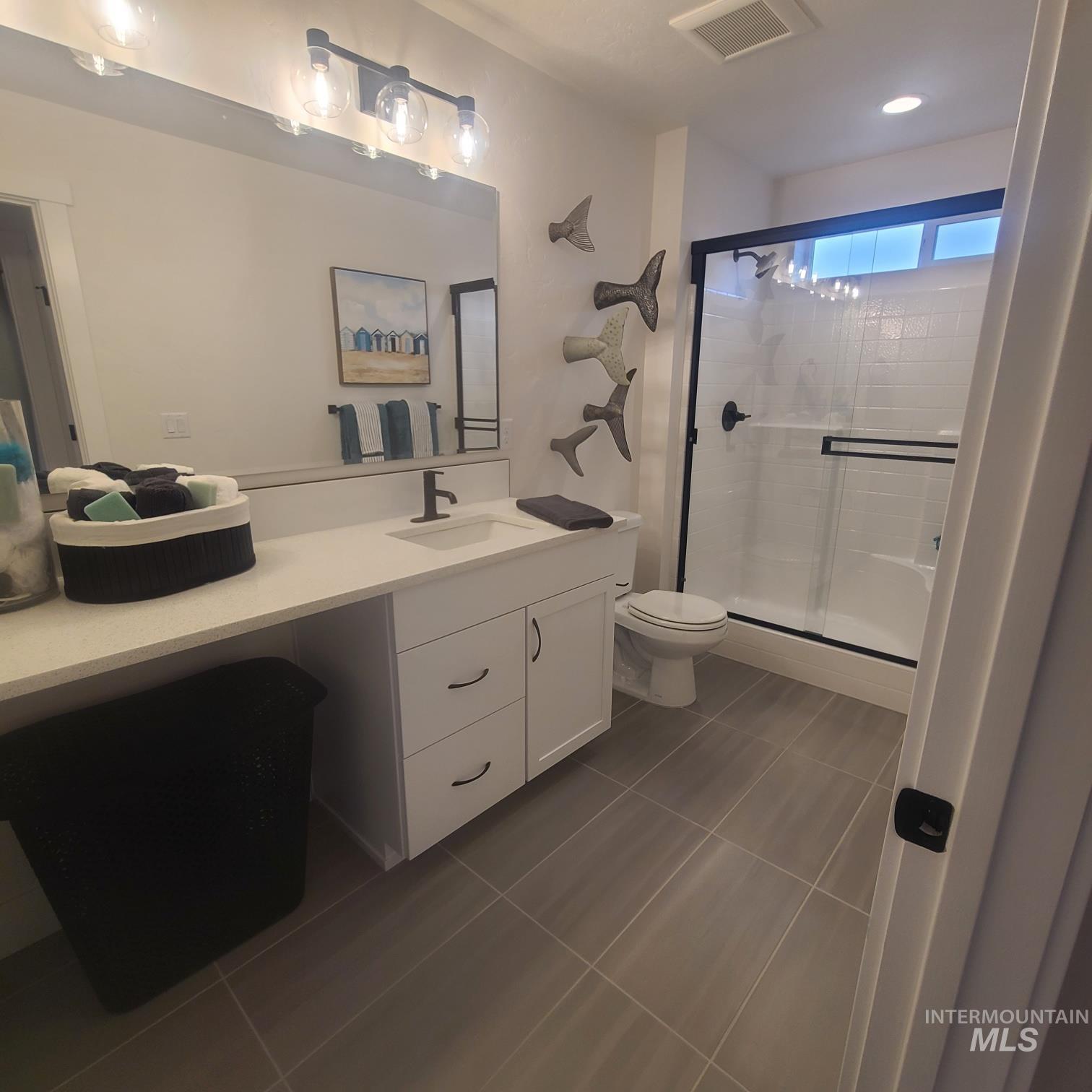 Full bathroom featuring vanity, light tile patterned flooring, and a shower stall
