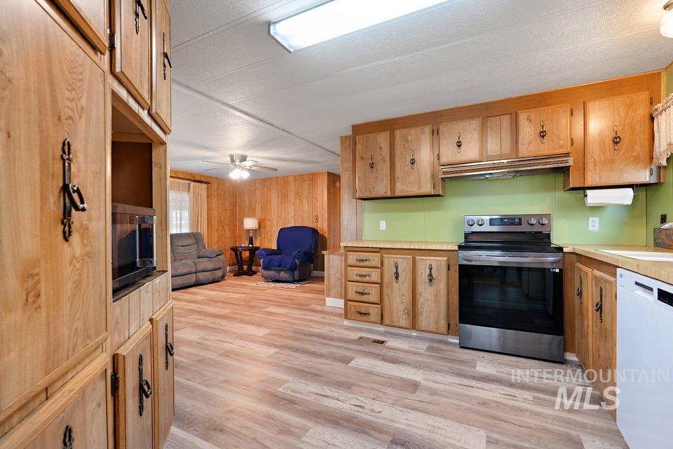 Kitchen with stainless steel range with electric stovetop, dishwasher, light wood-style flooring, open floor plan, and light countertops