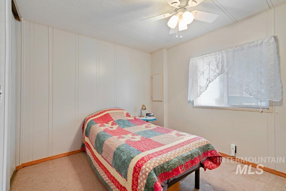 Bedroom with a decorative wall, a ceiling fan, and carpet floors