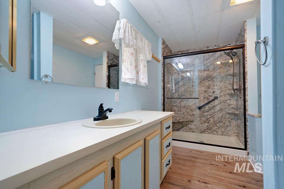 Bathroom with vanity, a marble finish shower, and light wood-style flooring