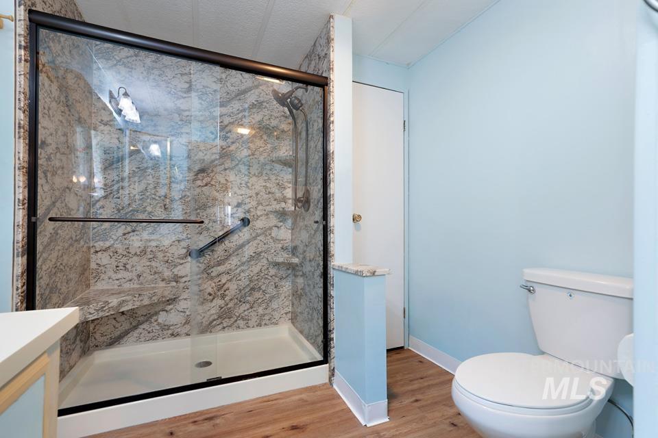 Full bathroom featuring a marble finish shower, wood finished floors, and vanity