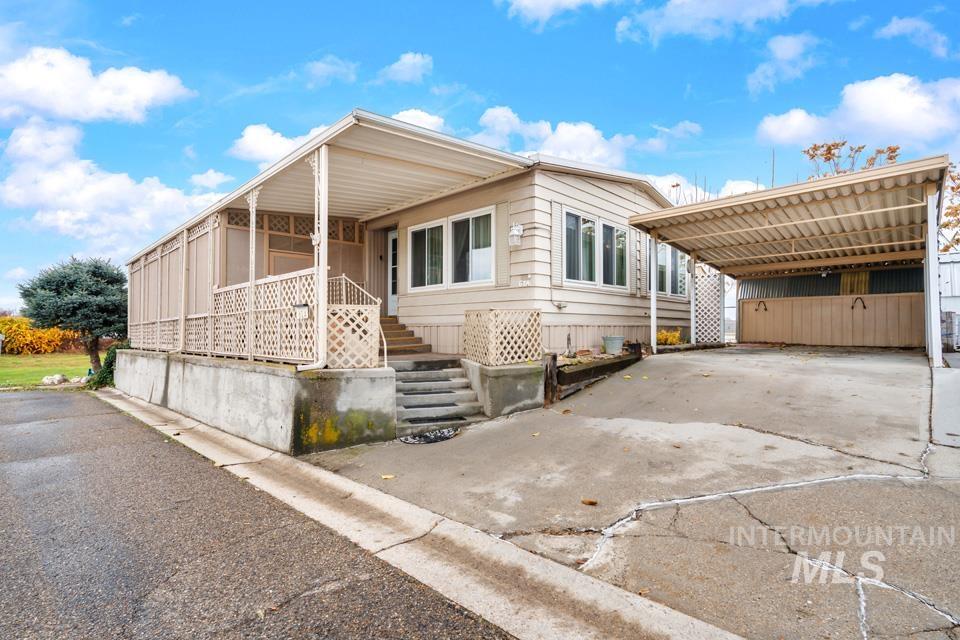 View of front facade with concrete driveway and a detached carport