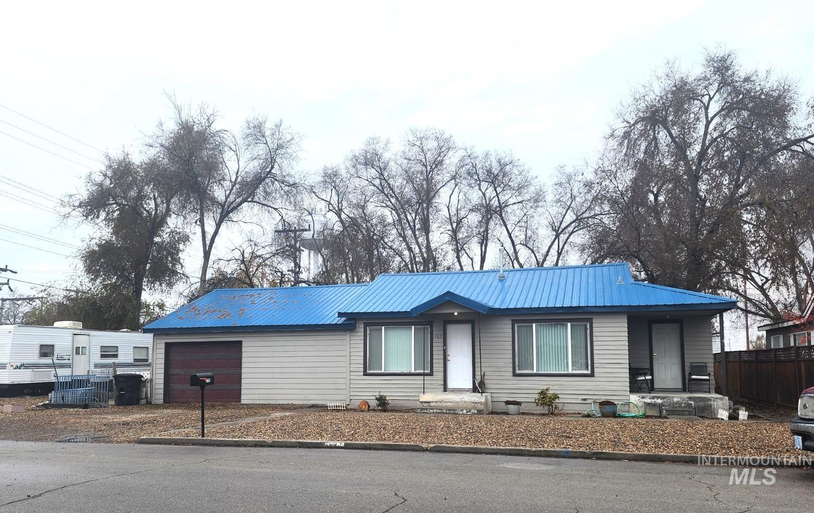 Single story home featuring an attached garage and a metal roof