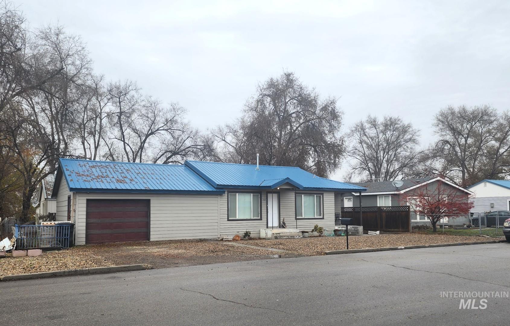 Ranch-style home featuring an attached garage, a metal roof, and driveway
