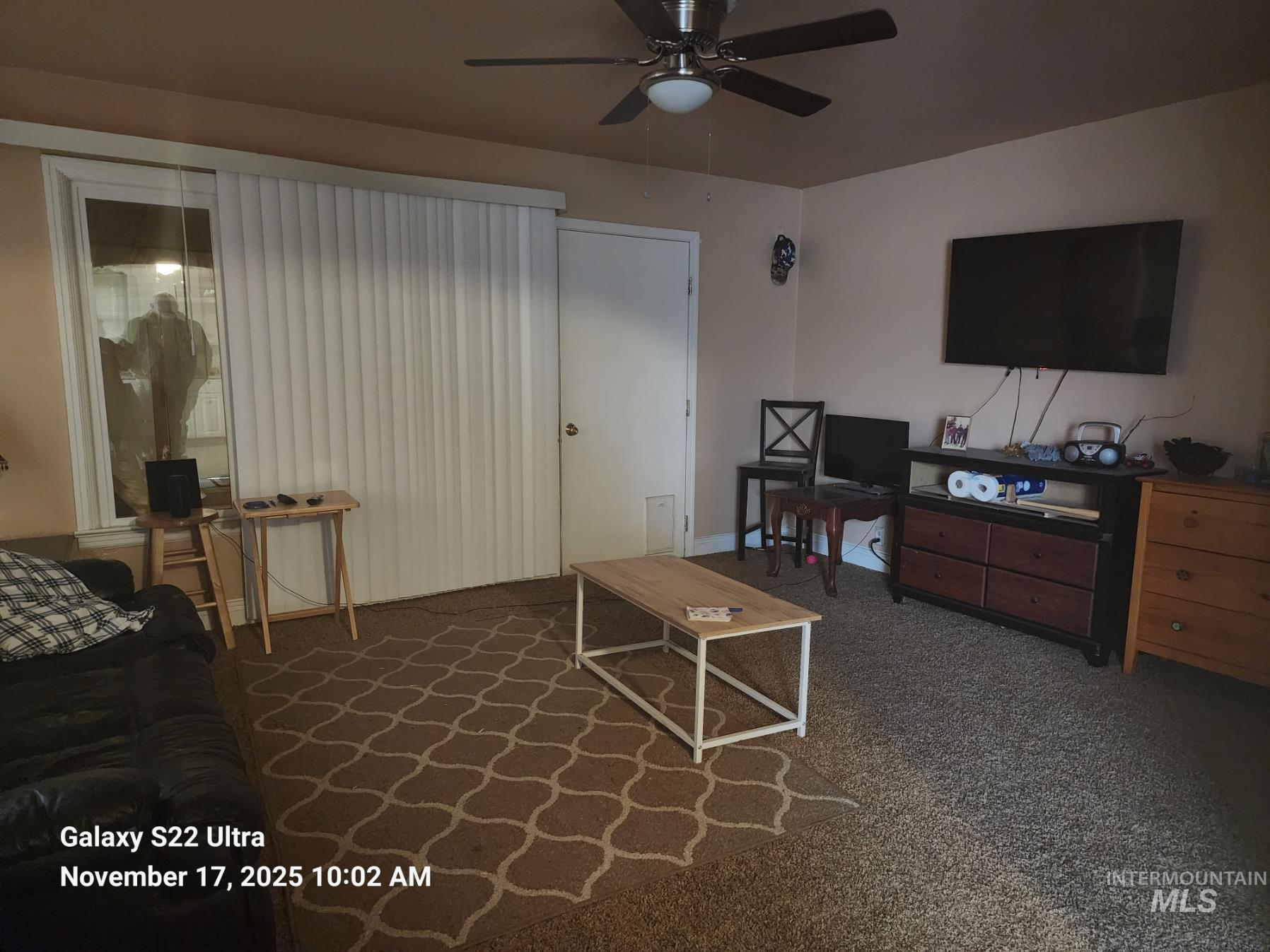 Living room featuring dark carpet and a ceiling fan