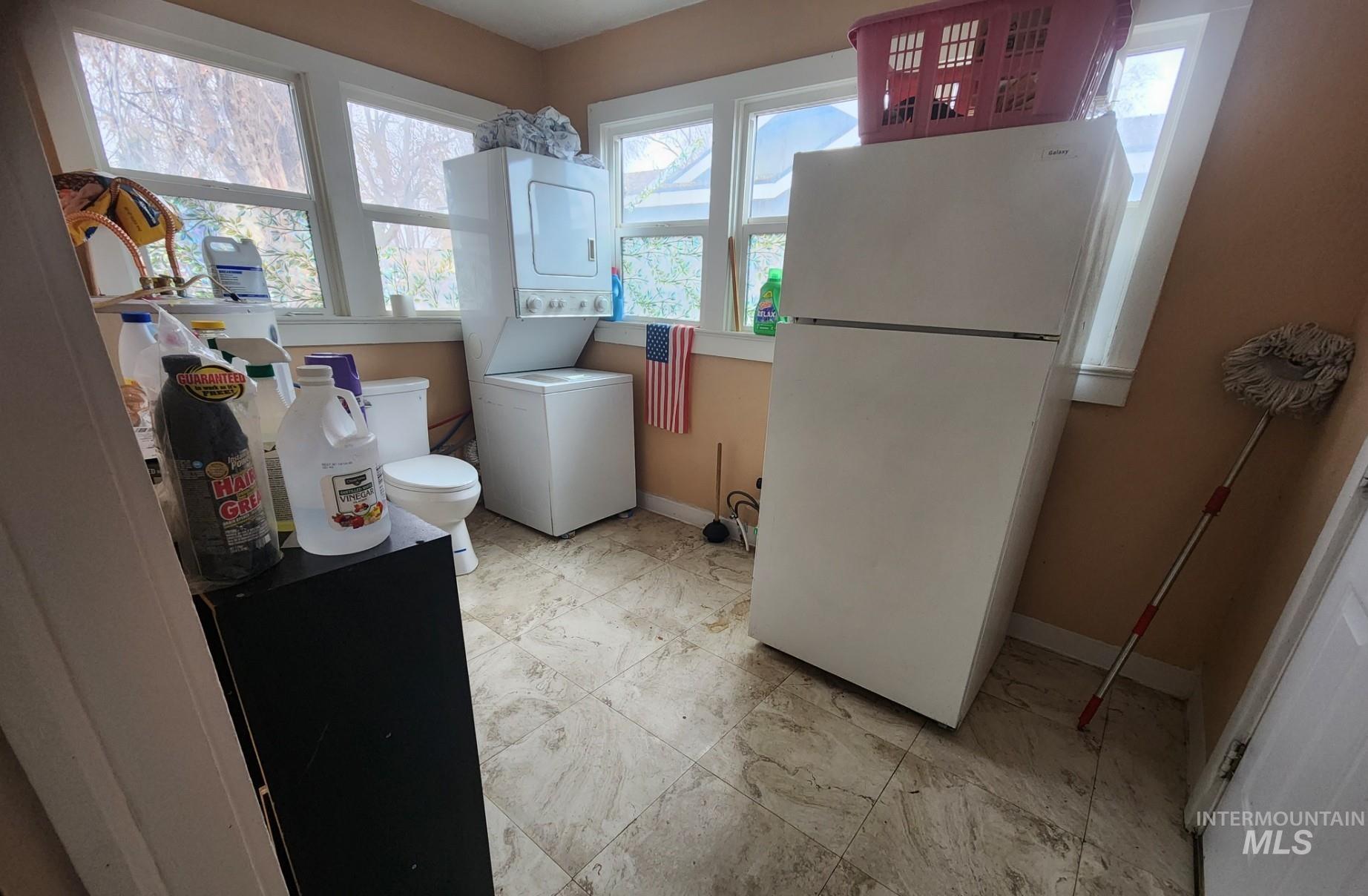 Washroom with estacked washer and dryer and baseboards