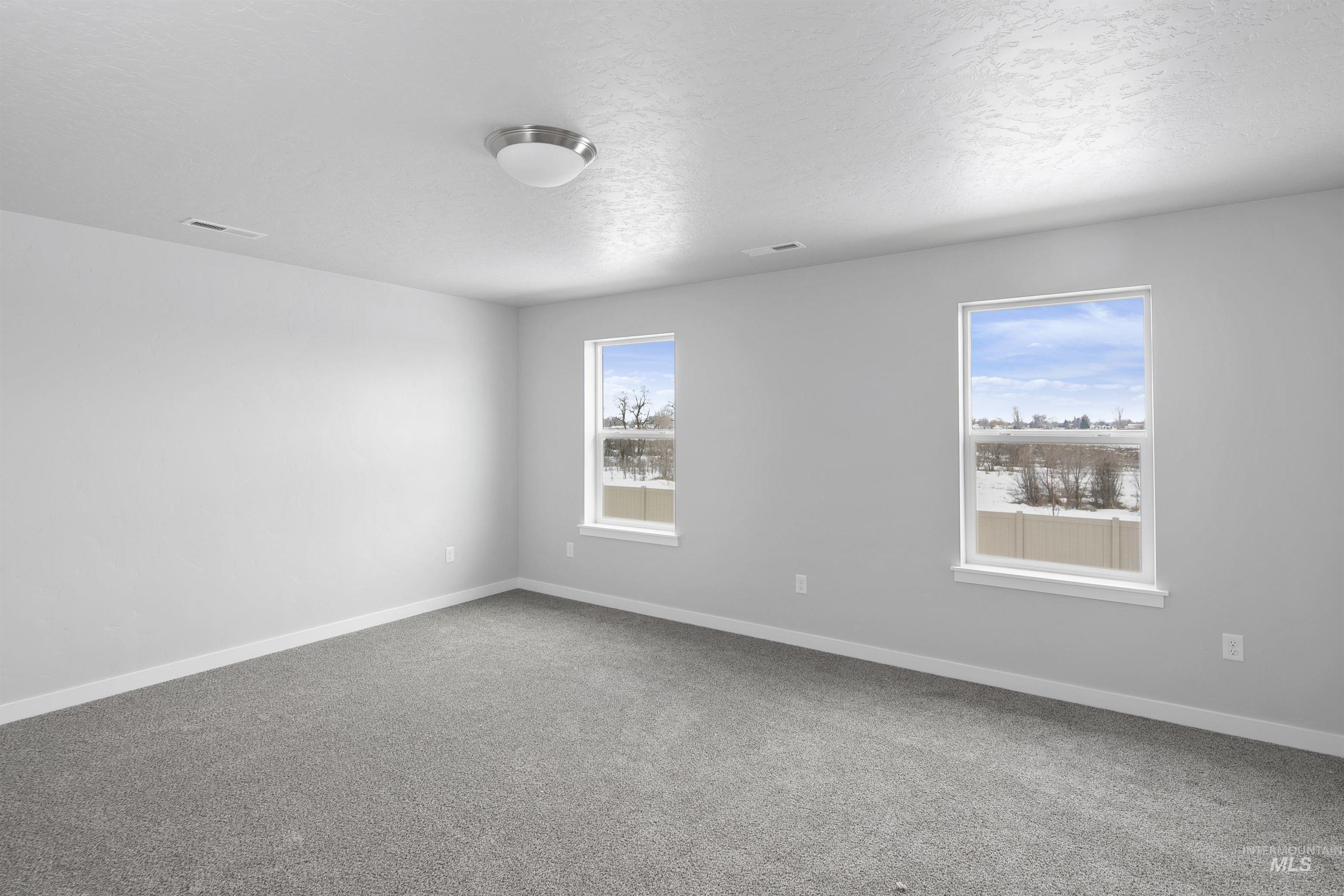 Carpeted empty room with baseboards and a textured ceiling