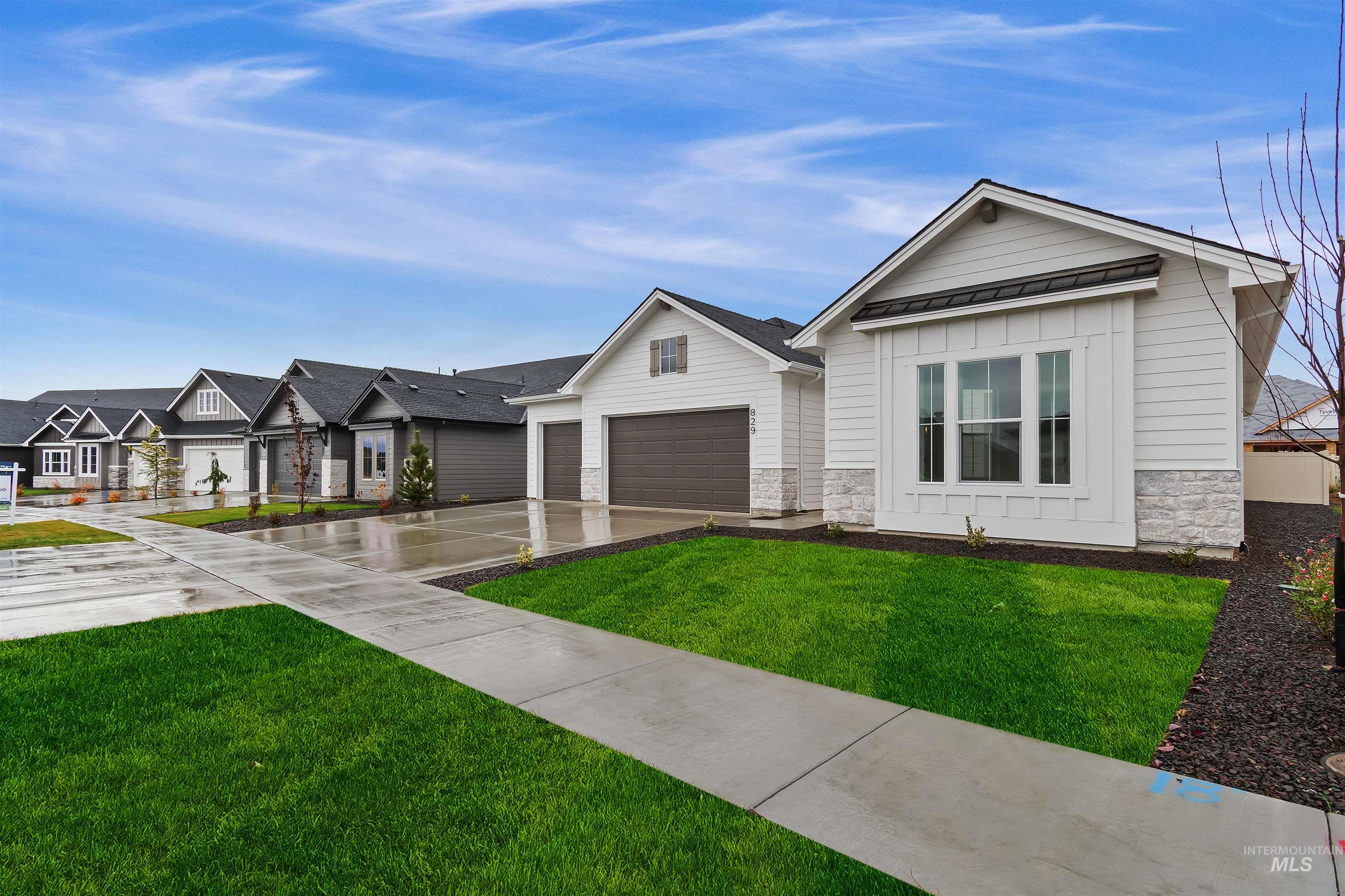 View of front facade featuring stone siding, a standing seam roof, driveway, a front yard, and a metal roof