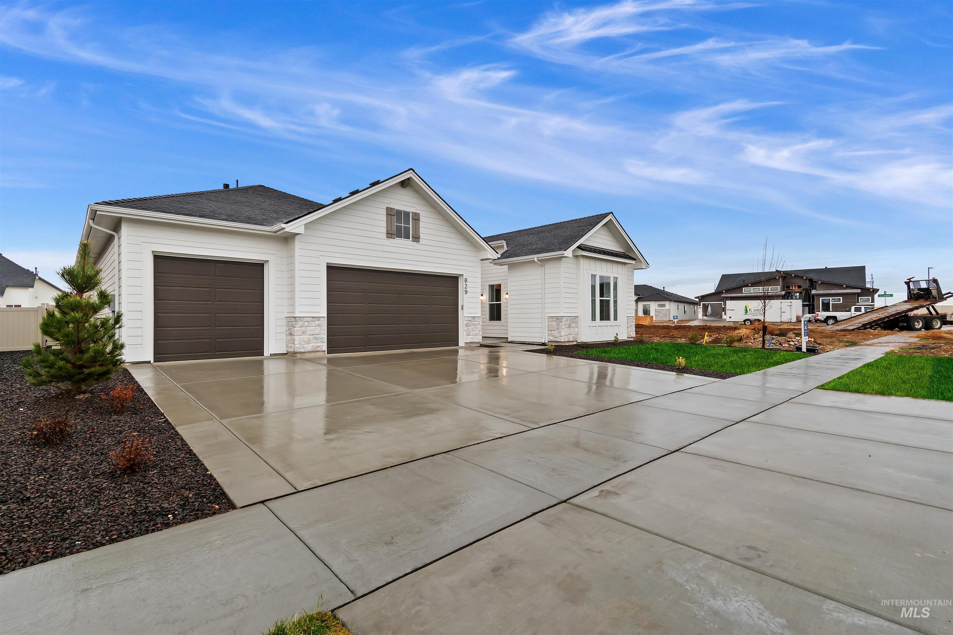 View of front of house featuring concrete driveway, roof with shingles, stone siding, and an attached garage
