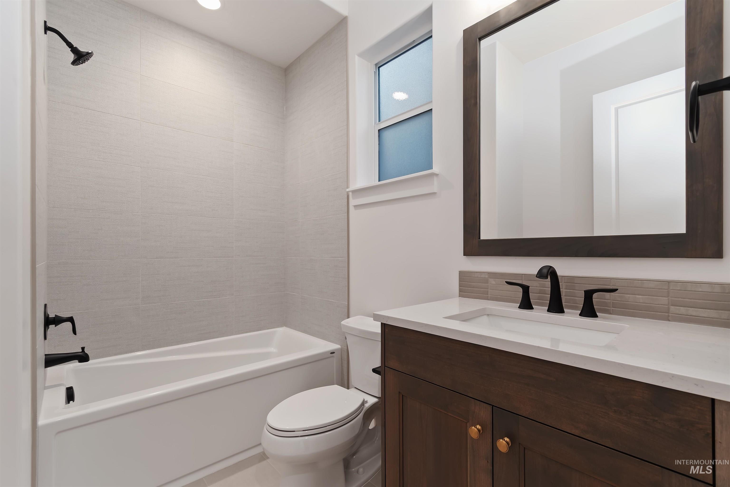 Bathroom with vanity, shower / washtub combination, and decorative backsplash