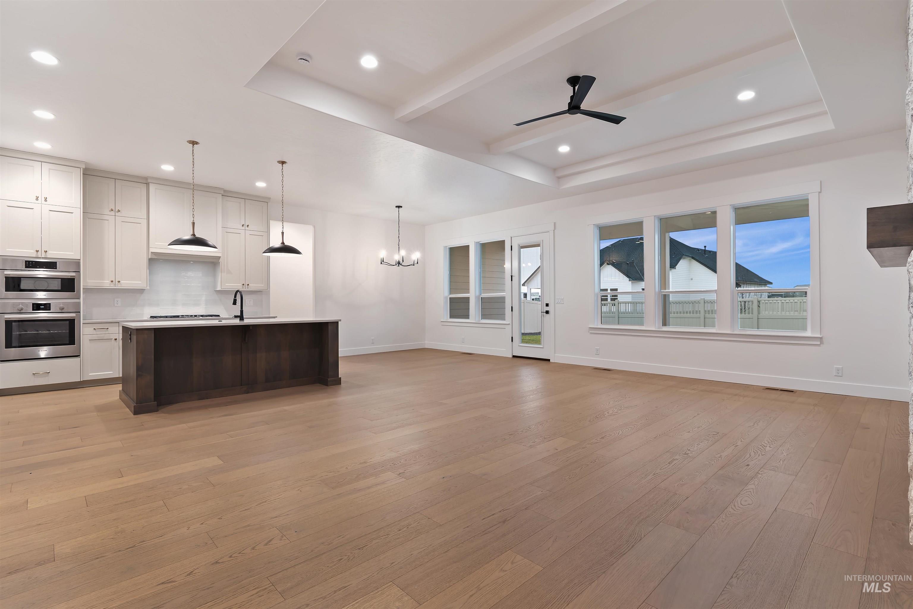 Unfurnished living room with a chandelier, light wood-style flooring, a ceiling fan, beam ceiling, and recessed lighting
